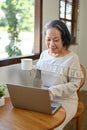 Successful aged Asian businesswoman working from home, sipping coffee while using laptop computer Royalty Free Stock Photo