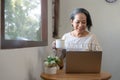 Portrait, Professional and successful aged Asian businesswoman working from home, sipping morning coffee while using Royalty Free Stock Photo