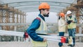 Portrait of professional surveyor walking outside construction site carrying equipment