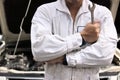 Portrait of professional young mechanic man in uniform holding wrench against car in open hood at the repair garage. Royalty Free Stock Photo