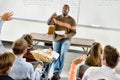 Portrait of Professor pointing at college student with hands raised in classroom