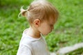 Portrait in profile of cute blond toddler girl in a windy summer day wearing ponytail