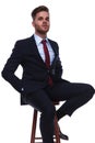 Portrait of proud businessman sitting on wooden stool