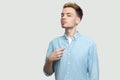 Portrait of proud handsome young man in light blue shirt standing, pointing himself and looking at camera with serious face Royalty Free Stock Photo