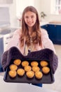 Portrait Of Proud Teenage Girl Taking Out Tray Of Homemade Cupcakes From The Oven At Home