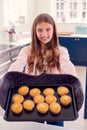 Portrait Of Proud Teenage Girl Taking Out Tray Of Homemade Cupcakes From The Oven At Home