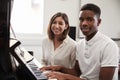 Portrait Of Pupil With Teacher Playing Piano In Music Lesson