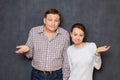 Portrait of puzzled couple shrugging shoulders and silly smiling Royalty Free Stock Photo