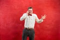 Portrait of puzzled man talking by phone a red background Royalty Free Stock Photo