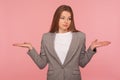 Portrait of puzzled uncertain young woman in business suit gesturing i don`t know, raising hands in bewilderment Royalty Free Stock Photo