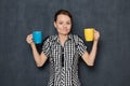 Portrait of puzzled young woman holding colored cups and doubting Royalty Free Stock Photo
