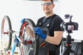 Qualified handyman fixing broken bicycle, filming process on videocamera