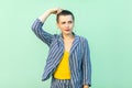 Portrait of query or confused handsome beautiful short hair young stylish woman in casual striped suit standing scratching her Royalty Free Stock Photo