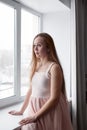 Portrait of real beautiful woman with long hair, looking out the window with anxiety Royalty Free Stock Photo