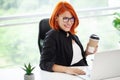 Portrait red-haired beautiful woman working in the office. Royalty Free Stock Photo