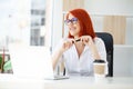 Portrait red-haired beautiful woman working in the office. Royalty Free Stock Photo