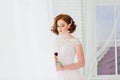 Portrait of red haired girl wearing wedding dress against a white studio background Royalty Free Stock Photo