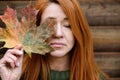 Portrait of red-haired middle-aged woman with closed eyes and maple leaf Royalty Free Stock Photo