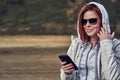 Portrait of a red-haired middle-aged woman in sunglasses and a raincoat looking at a smartphone. Sunny spring morning. Royalty Free Stock Photo