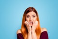 Portrait of red straight-haired attractive cute nice scared worried young girl, biting nails.  over bright vivid Royalty Free Stock Photo