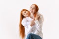 Portrait of redhaired mother and daughter in casual wear look at camera with smile, have good family relationship. Happy