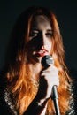 Portrait of redhead female singer woman in sparkly evening dress holding microphone. Singer at microphone. Woman singing Royalty Free Stock Photo