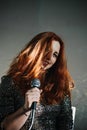 Portrait of redhead female singer woman in sparkly evening dress holding microphone. Singer at microphone. Woman singing Royalty Free Stock Photo