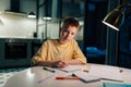 Portrait of redhead school boy pupil studying at home sitting at table under light of lamp, looking at camera. Smart Royalty Free Stock Photo