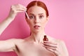portrait of redhead shirtless woman using cosmetics