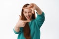 Portrait of redhead woman look through hands frames with creative eye, measure something, searching for perfect spot for