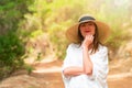 Portrait of a redhead woman in white dress and hat in the forest on a sunny day. Royalty Free Stock Photo