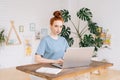 Portrait of redhead young businesswoman is working on laptop computer at the desk at home office. Royalty Free Stock Photo