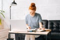 Portrait of redhead young woman student noting into the workbook important information from book Royalty Free Stock Photo