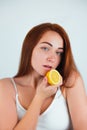 Portrait of redheaded young woman standing on isolated white background holding half of orange in hand near her face , beauty Royalty Free Stock Photo