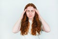 Portrait of redheaded young woman suffering from extreme headache looking upset standing on white backgroung, ,