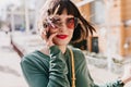 Portrait of refined european girl posing in windy spring day. Outdoor shot of adorable brunette lady in sunglasses and Royalty Free Stock Photo