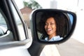 Reflection in side mirror of smiling african woman driving car Royalty Free Stock Photo