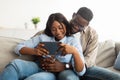 African american couple sitting on couch, using digital tablet Royalty Free Stock Photo