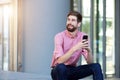 Relaxed man with beard sitting outside with cellphone Royalty Free Stock Photo