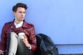 Portrait of a relaxed modern man sitting outdoors with cup of coffee and his backpack Royalty Free Stock Photo