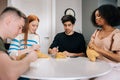 Portrait of relaxed multiethnic friends playing gambling board game sitting at table in living room. Playful multiracial Royalty Free Stock Photo