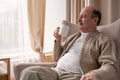 Portrait of relaxed senior man sitting on sofa with warm drink Royalty Free Stock Photo