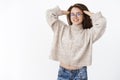 Portrait of relaxed tender attractive 20s woman in glasses and warm stylish sweater massaging hair and stretching