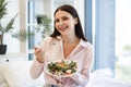 Portrait of relaxed woman sitting on comfy bed eating healthy salad. Royalty Free Stock Photo
