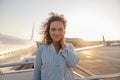 Portrait of relaxed woman smiling at camera while standing outdoors ready for boarding the plane at sunset