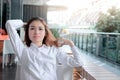 Portrait of relaxed young Asian business woman sitting and touch head with hands in office. Sunshine effect. Royalty Free Stock Photo