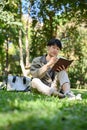 Portrait, Relaxed young Asian male college student chilling in the greenery park, reading a book Royalty Free Stock Photo