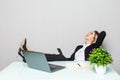 Portrait of a relaxed young businesswoman holding phone sitting with legs on desk in a office Royalty Free Stock Photo