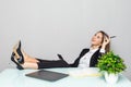 Portrait of a relaxed young businesswoman holding phone sitting with legs on desk in a office Royalty Free Stock Photo