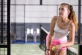 Relaxed sporty girl standing on paddle tennis indoor court leaning on net Royalty Free Stock Photo